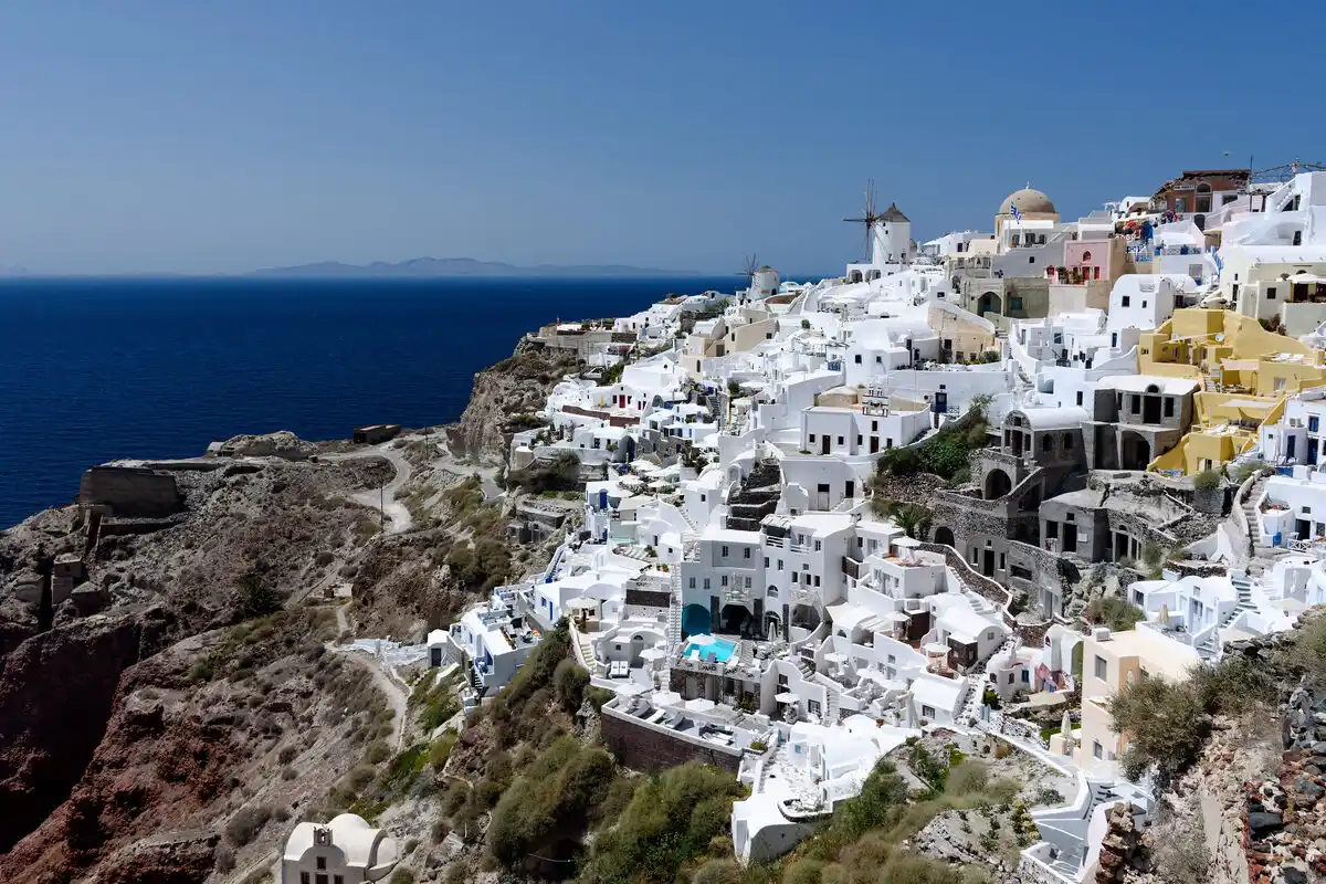 Whitewashed houses and a windmill of Oia village stacked along the Santorini caldera rim