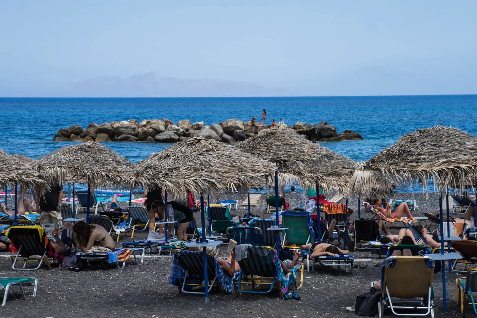 Kamari's black-sand beach with sunbeds beneath the Mesa Vouno headland