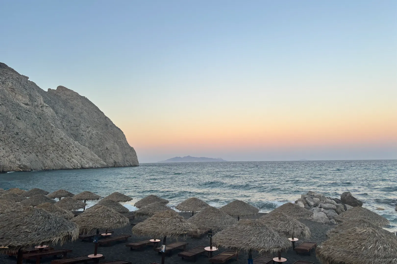 Perissa's dark sand beach and the Mesa Vouno headland at sunset