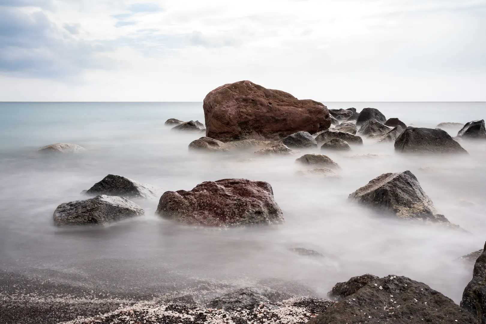 Wind-sculpted white pumice cliffs above the dark sand of Vlychada beach